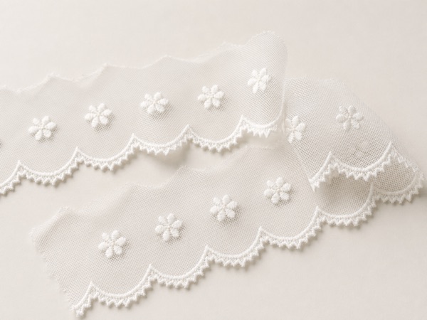 Embroidered tulle lace trims with delicate stitched floral patterns and scalloped edges.
