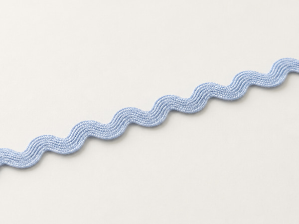 Zigzag rickrack trims in soft neutral colors arranged in loose curves.